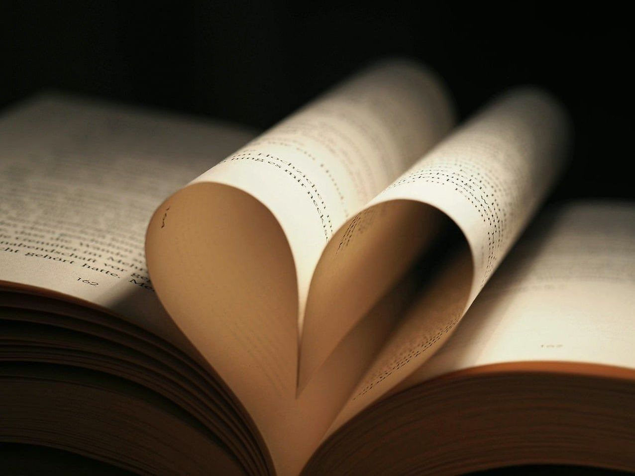 Islak bir masanın üzerinde eski bir kitap ve kalem